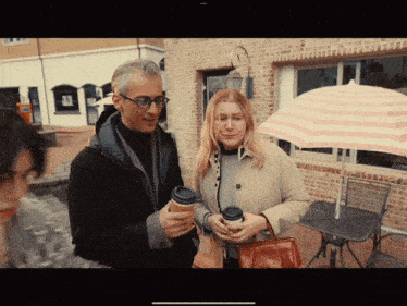 a man and a woman are standing under an umbrella in front of a building