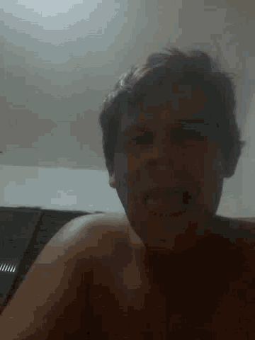 a man without a shirt is making a funny face with his mouth open .