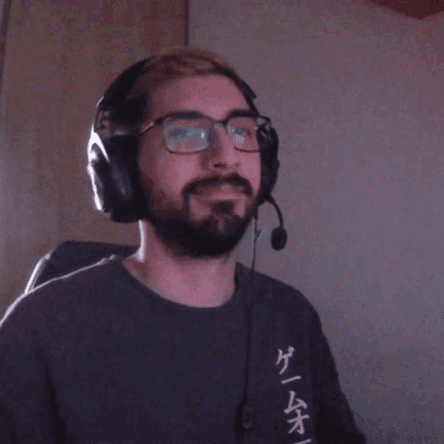 a man with a beard wearing headphones and giving a thumbs up