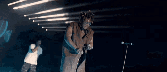 a man singing into a microphone while another man sings behind him