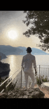 a man stands on a balcony overlooking the ocean