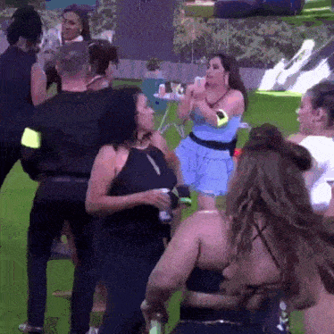 a group of women are dancing in a field while a man stands in the background .