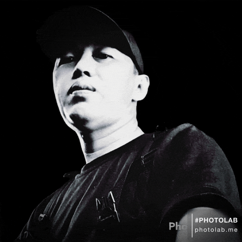 a black and white photo of a man wearing a hat and a black shirt