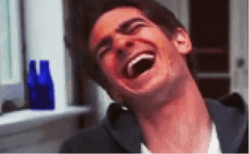 a man is laughing with his mouth open and his eyes closed in a room .
