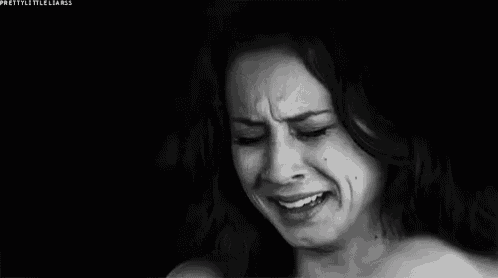 a woman is crying in a black and white photo while covering her face with her hand .