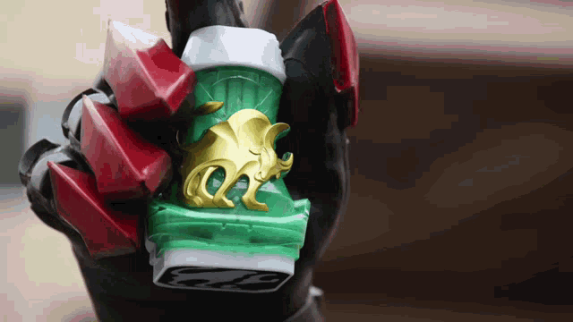 a person is holding a green and gold item with the letter o on it