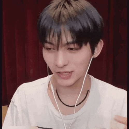a young man wearing headphones and a necklace .