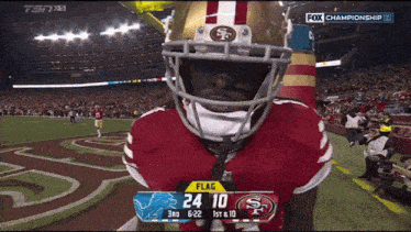 a football player wearing a 49ers helmet stands in front of a scoreboard