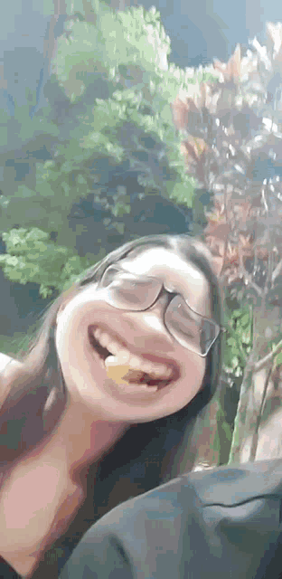 a woman wearing glasses is making a funny face while holding a piece of food in her mouth .