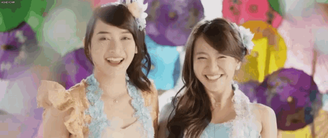 two women are standing next to each other in front of balloons and smiling .