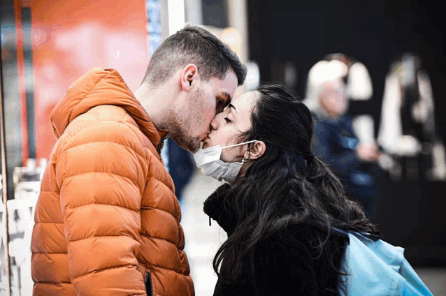 a man and woman wearing face masks are kissing
