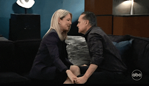 a man and a woman are sitting on a couch with abc written on the bottom right