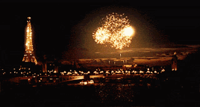 the eiffel tower is lit up at night with fireworks in the background