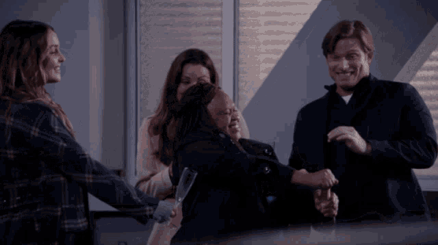 a group of people are hugging each other and one of them is holding a glass