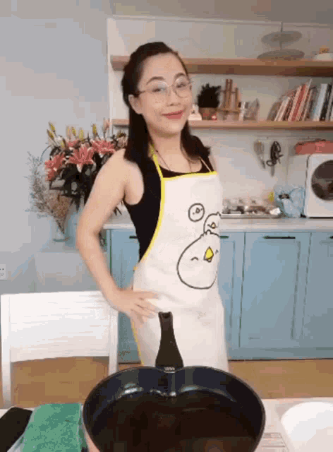 a woman wearing an apron with an angry bird on it stands in front of a frying pan