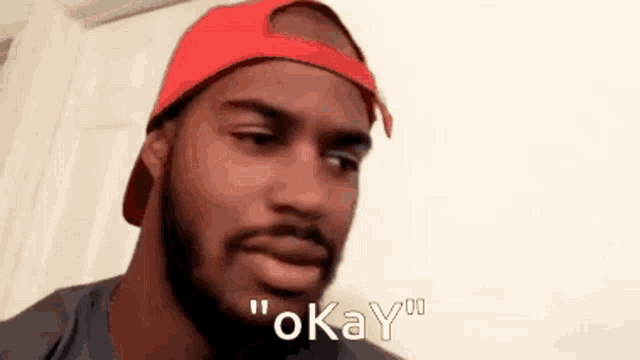 a man wearing a red hat says " okay "