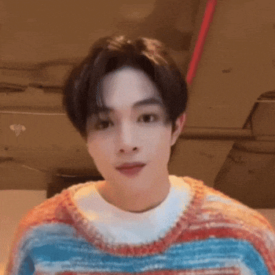 a young man is wearing a colorful sweater and a white shirt .