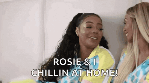 two women are sitting next to each other on a bed and one of them is saying `` rosie & i chillin at home ! ''