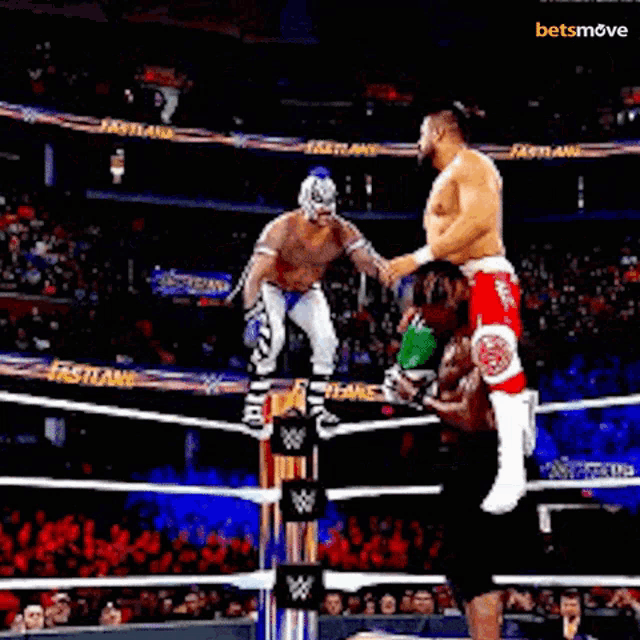 two men are wrestling in a wrestling ring and one of them is doing a flip over the other .