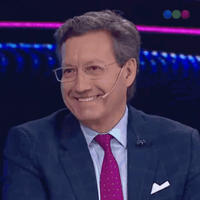 a man in a suit and tie is smiling with a microphone on his ear
