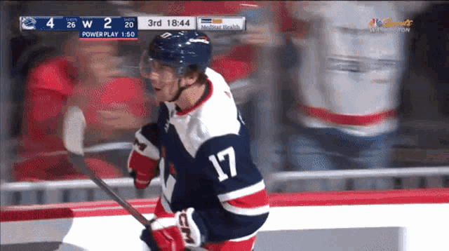 a hockey player with the number 17 on his jersey stands on the ice