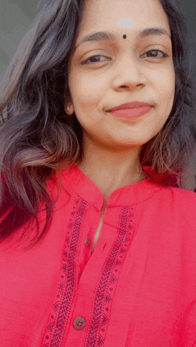 a woman wearing a red shirt has a nose ring on her nose