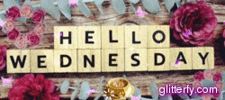 the words hello wednesday are written in scrabble tiles on a wooden table with flowers .