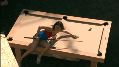 a woman is sitting on a pool table holding a cue