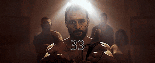a man with glasses and a beard has the number 33 on his chest .