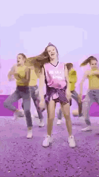 a girl in a pink shirt is dancing with a group of other girls .