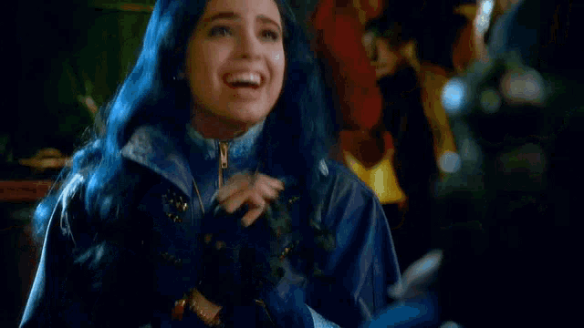 a woman with blue hair is wearing a jacket and a necklace .