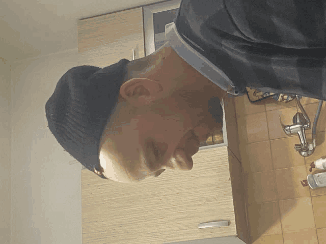 a man wearing a black beanie looks down at something
