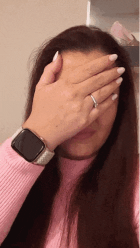 a woman wearing a watch and a ring is covering her face