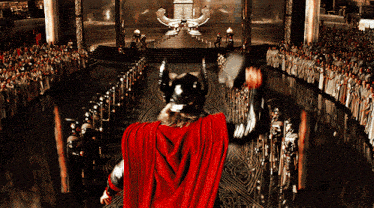a man in a red cape is holding a hammer in front of a large crowd
