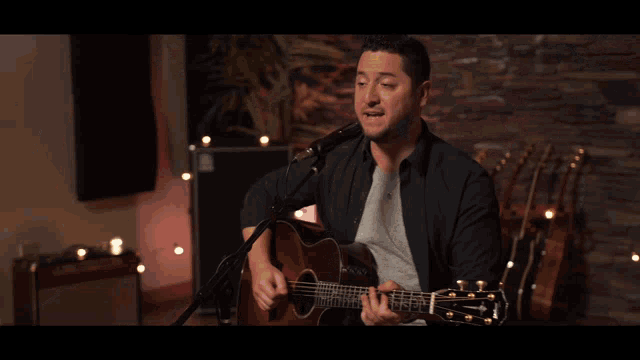 a man playing a guitar in front of a microphone