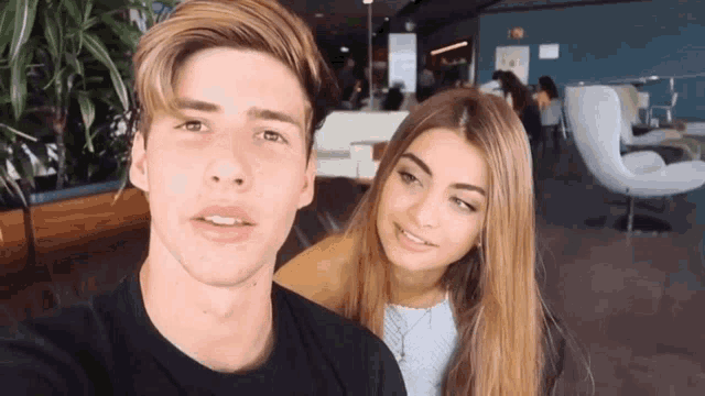 a man and a woman are posing for a picture and the man is wearing a black t-shirt