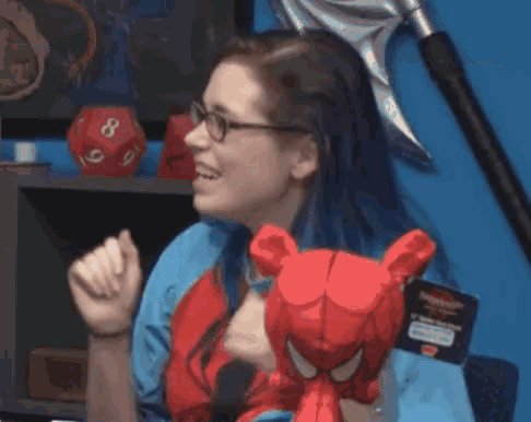 a woman wearing glasses is holding a stuffed spider man head