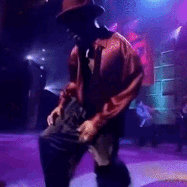 a man wearing a hat and a red shirt is dancing on a stage