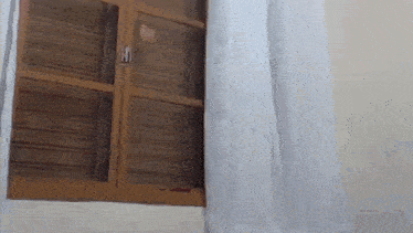 a wooden window with a white curtain behind it