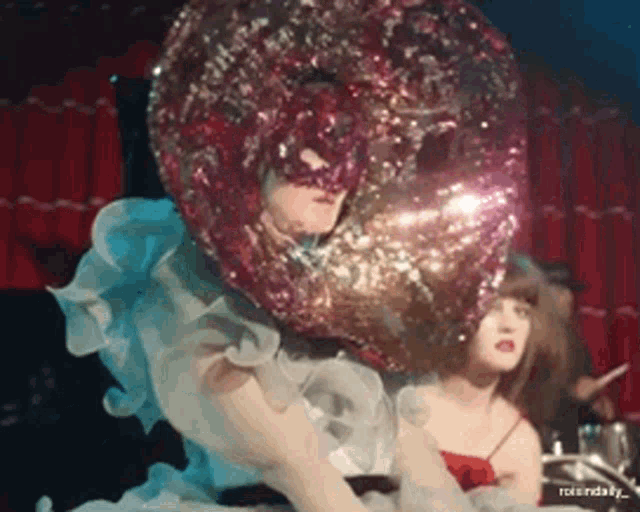 a woman is wearing a mask with a balloon on her head