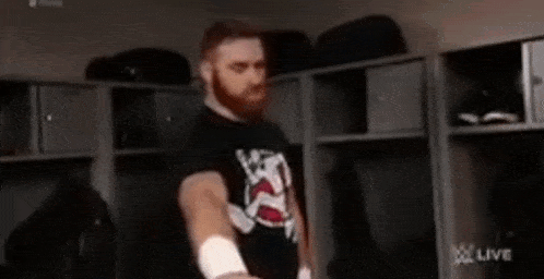 a man with a beard is standing in a locker room holding a towel .