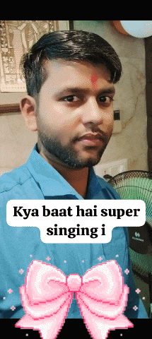 a man with a beard is standing in front of a fan with a pink bow behind him