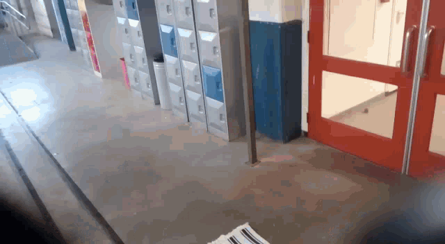 a row of lockers are lined up in a hallway next to a red door
