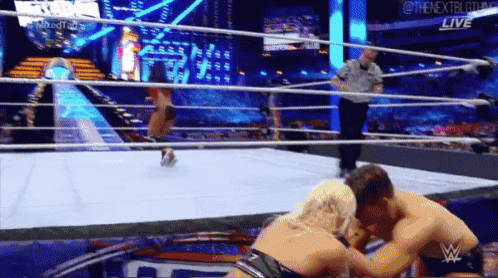 two men are wrestling in a wrestling ring while a referee watches .