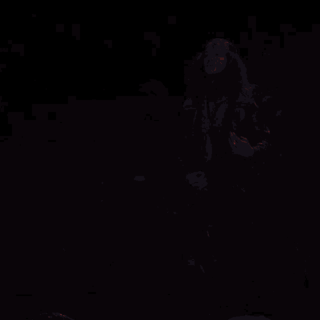 a man with long hair is playing a guitar in the dark
