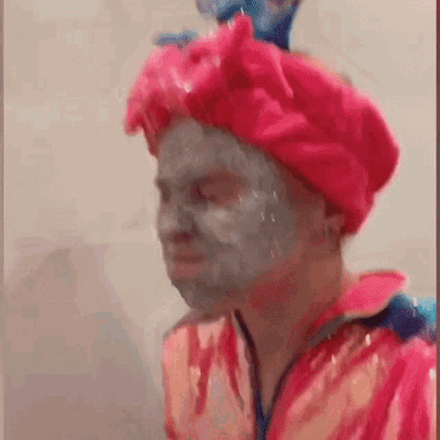 a man wearing a pink hat and a face mask is standing in front of a wall .