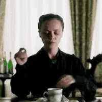 a woman is sitting at a table with a cup of coffee in her hand .