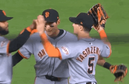 a baseball player with the number 5 on his back is giving another player a high five