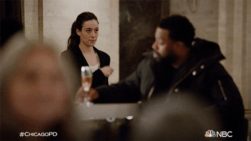 a man and a woman are sitting at a table with a glass of champagne in front of them and the hashtag #chicagopd