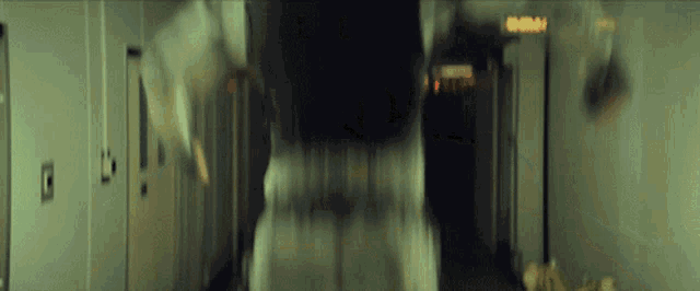 a blurry picture of a person walking down a hallway with a sign that says emergency exit